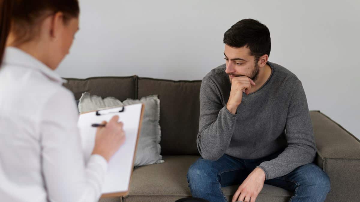 Male patient during individual therapy in a rehab center discussing with therapist topics like "my husband's drinking is ruining our marriage", and other alcohol addiction issues.